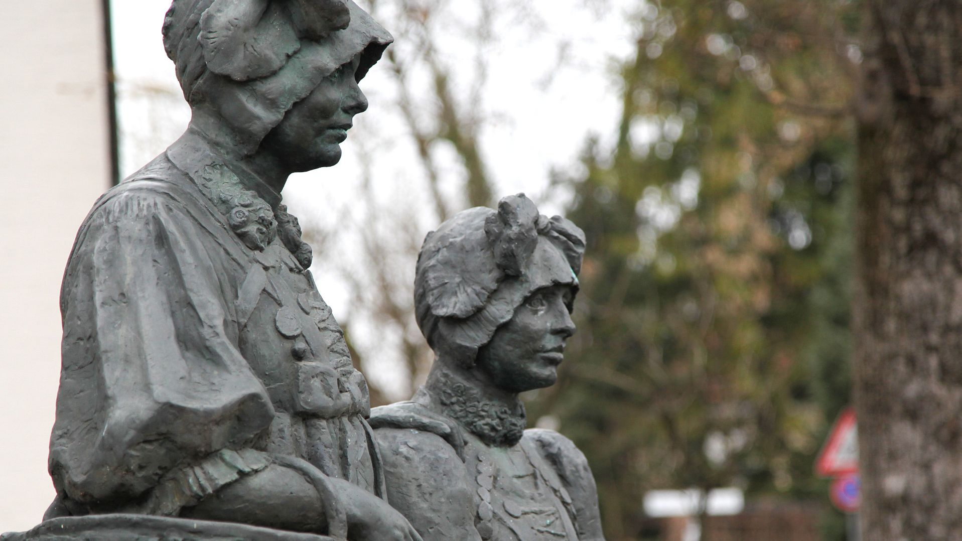 Bronze-Skulptur zweier Frauen in Dachauer Tracht, eine stehend, eine sitzend.